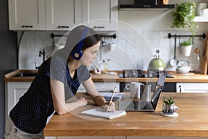 Busy engaged college student girl in wireless headphones using laptop