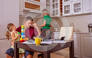 Busy Family Home with Father Working as Mother Prepares Meal