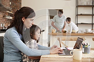 Busy Family Home With Mother Working As Father Prepares Meal