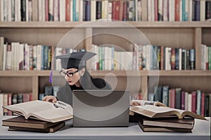 Busy graduate reading books at library