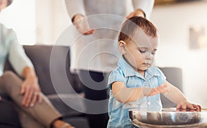 Busy hands are learning hands. an adorable baby girl banging playfully on a table with her family in the background.