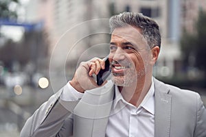 Busy happy middle aged business man making call talking on phone on city street.