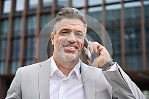 Busy happy middle aged business man making call talking on phone outdoors.