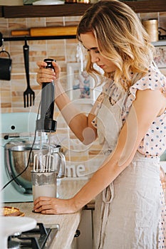 Busy hardworking woman with beautiful hair mixing in a container in a kitchen corner