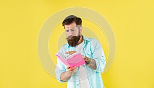 busy hipster guy reading notebook on yellow background, erudition