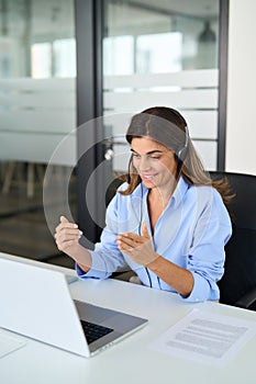 Busy Hispanic woman call center support agent working using laptop in office.