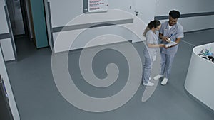 Busy hospital hallway: Medical personnel walking, talking about work