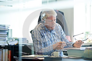 Busy on an important call. A senior businessman sitting in his office wearing a headset.