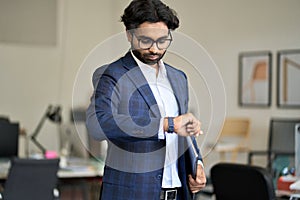 Busy indian business man checking time looking at watch in office.