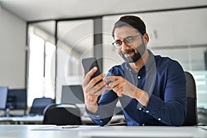 Busy Indian business man executive using mobile phone working in office.