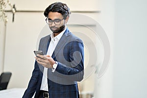 Busy indian business man using smartphone working standing in office.