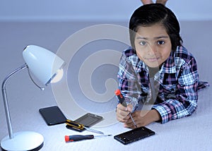 Busy kid fixing mobile phone with screwdriver