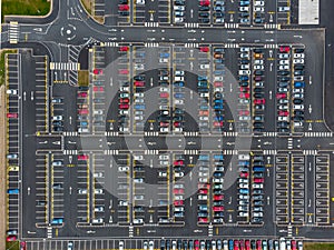 Busy large modern carpark with symmetrical roads rows of parking bays lots of symmetry and colours aerial view from drone up above