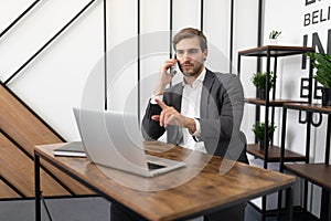 busy lawyer talking on the phone in the office with a client and looking at a laptop