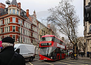 Busy London intersection on overcast wet winter day with people on bikes and double decker bus on the street - selective focus