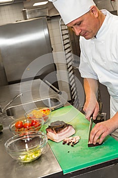 Busy male cook cutting meat in kitchen