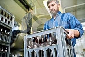 Busy male mover transporting box with beer bottles from plant