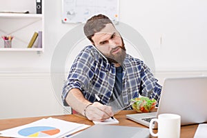 Busy man has vegetarian lunch in modern office interior