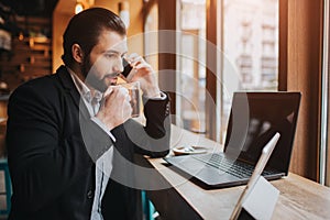 Busy man is in a hurry, he does not have time, he is going to eating and working. Worker eating, drinking coffee