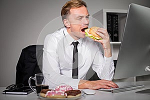 Busy man at the office eating fast food