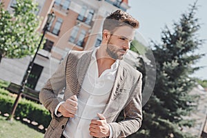 Busy man. Serious brown-haired man standing in the park in the morning going to work