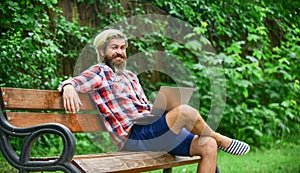 Really busy. mature man sitting on park bench with laptop and checking email. Freelancer man working on computer