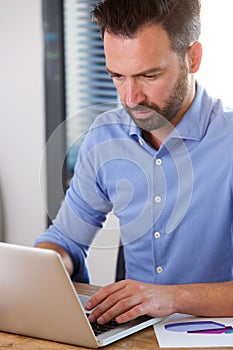 Busy mature man working on laptop at his desk