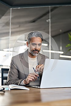 Busy middle aged business man looking at laptop working in office. Vertical.