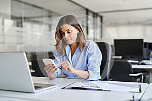 Busy middle aged business woman using mobile phone working in office.