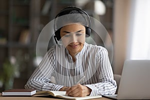 Busy millennial hindu female in wireless headset work using laptop