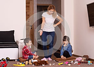 Busy mom. Mom tired to tidy up the house. Child scattered toys. Mess in the house.