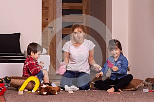 Busy mom. Mom tired to tidy up the house. Child scattered toys. Mess in the house.