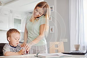 Busy mother feeding child and talking on the phone