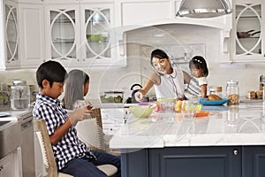 Busy Mother Organizing Children At Breakfast In Kitchen photo