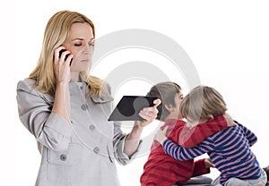 Busy mother with tablet and mobile while her children fighting