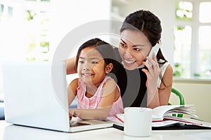 Busy Mother Working From Home With Daughter