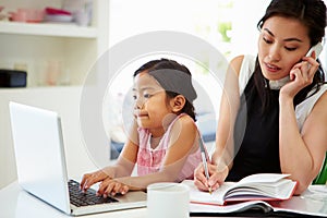 Busy Mother Working From Home With Daughter