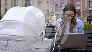 Busy office employee struggling work on laptop and taking care on infant in pram