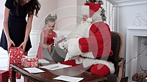 Busy Santa answering chidlren`s letters while Santa`s little helpers bringing more presents