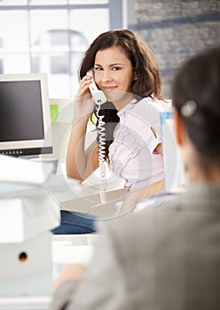 Busy secretary talking on phone in office smiling