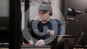 Busy security worker in headphones sits and typing keyboard