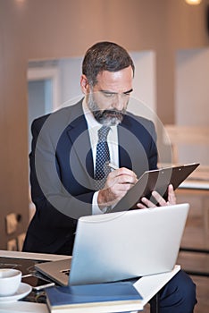 Busy senior business man in a coffee shop