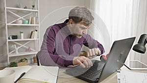 Busy serious Caucasian man typing on laptop keyboard, checking time on watch, and leaving. Portrait of concentrated