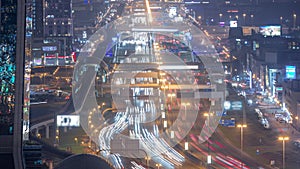 Busy Sheikh Zayed Road aerial night timelapse, metro railway and modern skyscrapers around in luxury Dubai city.