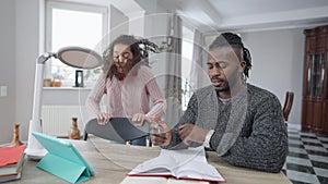 Busy single father working from home as bored irritated teenage daughter distracting parent from work. African American