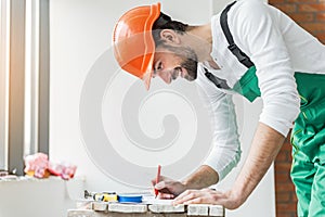 Busy smiling builder absorbedly writing