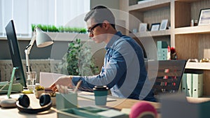 Busy startuper flipping notebook pages at computer table. Serious man working