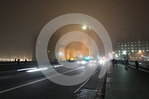 Busy street with traffic and pedestrians at foggy night in London