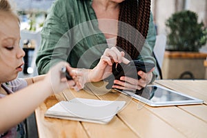 Busy Successful Mother and Business Owner with cell phone and tablet having breakfast with her little baby daughter in