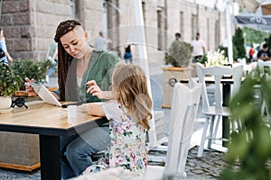 Busy Successful Mother and Business Owner with cell phone and tablet having breakfast with her little baby daughter in